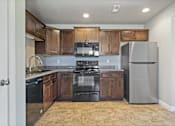 Thumbnail 32 of 47 - A kitchen with black appliances and wooden cabinets.