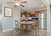 Thumbnail 2 of 47 - Townhomes for Rent in Peculiar, MO - Bradley’s Crossing - Dining Room with High Ceiling, Ceiling Fan with Light, Vinyl Plank Flooring, 4-Seater Dining Table and Chairs, Round Rug, and Wall Art.