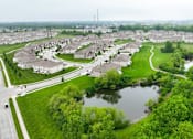 Thumbnail 23 of 23 - A bird's eye view of a residential area with houses, a pond, and a road.