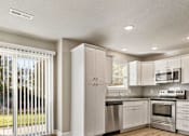 Thumbnail 13 of 23 - A modern kitchen with white cabinets and stainless steel appliances.