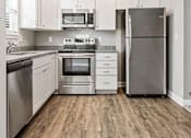 Thumbnail 7 of 23 - Townhomes for Rent in Belton, MO - Traditions Townhomes - Kitchen with Vinyl Plank Flooring, High Ceiling, Granite Countertop, White Cabinetry, and Stainless Steel Appliances.