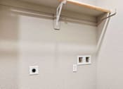 Thumbnail 16 of 23 - A white wall with a shelf and two electrical outlets.