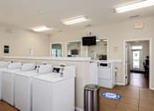 Thumbnail 13 of 28 - A laundromat with rows of washers and dryers.