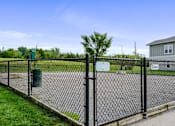 Thumbnail 9 of 28 - Lawrence, KS, Apartments for Rent - Remington Square - Dog Park with Gravel Ground, Pet Waste Station, Concrete Blocks, Landscaping, and Black Metal Fence.