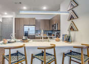 Thumbnail 1 of 29 - A kitchen with a white countertop and wooden chairs.