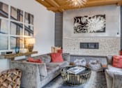 Thumbnail 22 of 29 - A living room with grey couches and a fireplace.