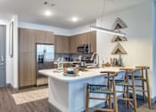Thumbnail 2 of 29 - A kitchen with a white counter and wooden chairs.