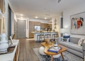 Thumbnail 3 of 29 - A modern living room with a grey sofa, a wooden coffee table, and a large abstract painting on the wall.