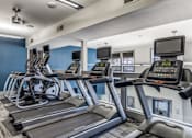 Thumbnail 8 of 32 - A gym with treadmills and elliptical machines.