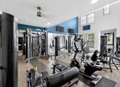 Thumbnail 28 of 32 - A gym with a variety of equipment including a squat rack, a leg press machine, and a bench press.