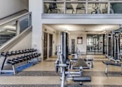 Thumbnail 11 of 32 - A spacious gym with a variety of equipment and a staircase.