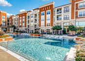 Thumbnail 2 of 32 - A large swimming pool in front of apartment buildings.