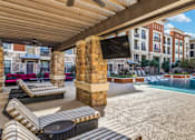 Thumbnail 4 of 32 - A pool area with sun loungers and a building in the background.