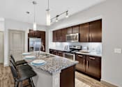 Thumbnail 19 of 32 - A kitchen with brown cabinets and a granite countertop.