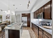 Thumbnail 24 of 32 - A modern kitchen with dark wood cabinets and stainless steel appliances.