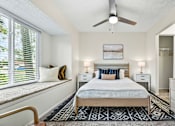 Thumbnail 36 of 41 - A bedroom with a bed, two nightstands, a ceiling fan, and a window with blinds.