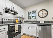 Thumbnail 34 of 41 - A modern kitchen with white cabinets and black appliances.