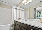 Thumbnail 23 of 41 - A bathroom with a white tub, sink, and a mirror.