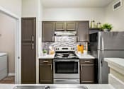 Thumbnail 17 of 41 - A kitchen with a stove top oven and a refrigerator.