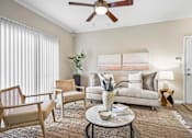 Thumbnail 12 of 41 - A living room with a white couch, a coffee table, and a ceiling fan.