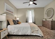 Thumbnail 25 of 41 - A bedroom with a bed, nightstand, and a ceiling fan.