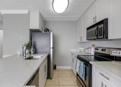 Thumbnail 4 of 22 - A kitchen with a refrigerator, microwave, and oven.