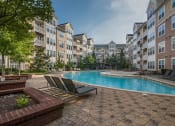 Thumbnail 30 of 39 - an apartment building with a pool and lounge chairs