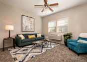 Thumbnail 4 of 28 - A living room with a green couch, a blue couch, a rug, and a ceiling fan.