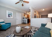 Thumbnail 2 of 28 - A living room with a blue couch, a white vase, and a ceiling fan.