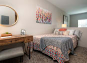 Thumbnail 8 of 28 - A bedroom with a bed, desk, chair, and a painting on the wall.