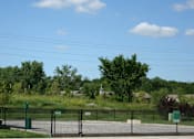 Thumbnail 25 of 28 - A fenced area with a sign and trees in the background.