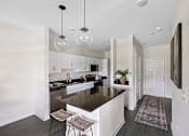 Thumbnail 7 of 26 - A modern kitchen with a black countertop and white cabinets.