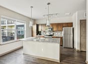 Thumbnail 32 of 39 - A kitchen with a large island and stainless steel appliances.