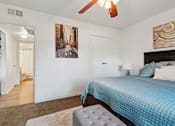 Thumbnail 11 of 19 - A bedroom with a bed, a ceiling fan, and a painting on the wall.