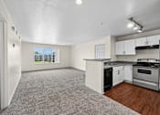 Thumbnail 4 of 25 - A spacious living area with a kitchen and a view of a parking lot through the window.