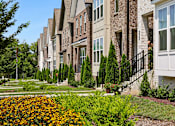 Thumbnail 139 of 149 - A row of townhouses with a flower bed in the foreground.