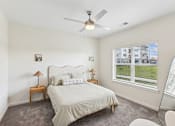 Thumbnail 15 of 36 - A bedroom with a large bed, a ceiling fan, and a window with blinds.