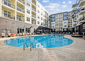 Thumbnail 23 of 39 - A large swimming pool in front of apartment buildings.