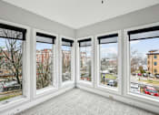 Thumbnail 10 of 13 - A room with four large windows overlooking a street.