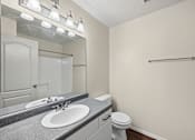 Thumbnail 19 of 25 - A bathroom with a sink, toilet, and mirror.