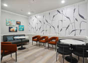 Thumbnail 12 of 25 - a waiting room with tables and chairs and a wall with a painting
