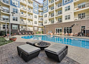 Thumbnail 26 of 39 - A pool surrounded by a patio with two lounge chairs and a fire pit.