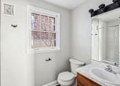 Thumbnail 9 of 15 - A white bathroom with a toilet, sink, and window.