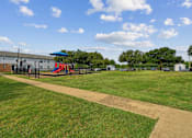 Thumbnail 17 of 19 - A playground with a slide and a building in the background.