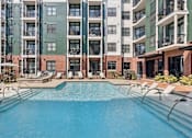 Thumbnail 14 of 66 - A large swimming pool in front of apartment buildings.
