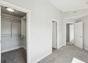Thumbnail 19 of 27 - A white room with a walk-in closet and a carpeted floor.