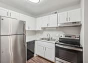 Thumbnail 4 of 11 - A kitchen with a stainless steel refrigerator, oven, and cabinets.