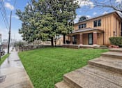 Thumbnail 3 of 13 - A house with a green lawn and a tree in front.