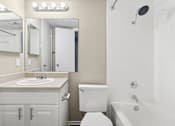 Thumbnail 7 of 14 - A white bathroom with a sink, toilet, and bathtub.
