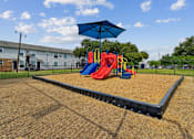 Thumbnail 14 of 19 - A playground with a slide, swings, and a blue umbrella.